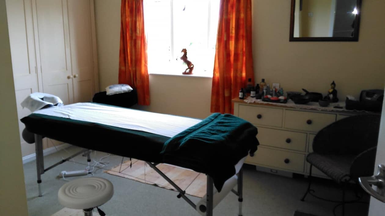 massage bench in studio - large window,  with iron leaping horse sculpture on window sill.